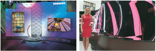 삼성전자처음으로 공개하는 QLED 사이니지는 삼성전자가 올 초 세계 최대의 가전 전시회 '소비자가전쇼(CES) 2017'에서 공개한 QLED TV의 최첨단 신소재 메탈 퀀텀닷(양자점) 기술을 그대로 적용한 상업용 디스플레이 제품이다. 삼성 QLED 사이니지 모습(왼쪽). LG전자 모델이 앞뒤 동시에 화면을 볼 수 있는 물결형태의 'LG 양면 올레드 사이니지'를 소개하고 있다. 삼성전자·LG전자 제공